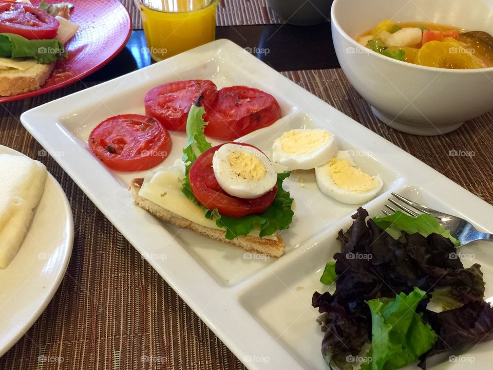 Grilled tomato cheese boiled egg with fresh fruit salad for breakfast 