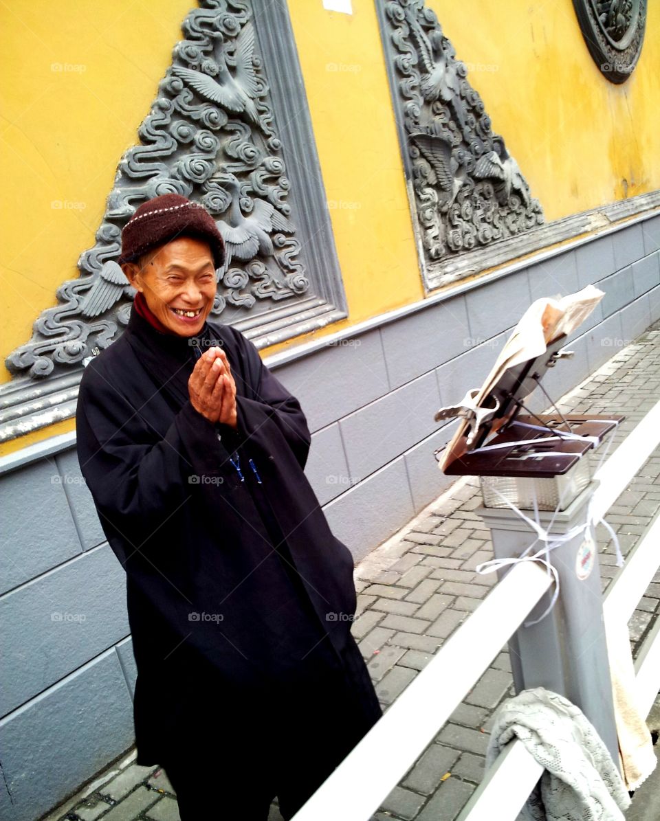 Chinese Old Man praying along the street by the Jade Buddha Temple in Shanghai
