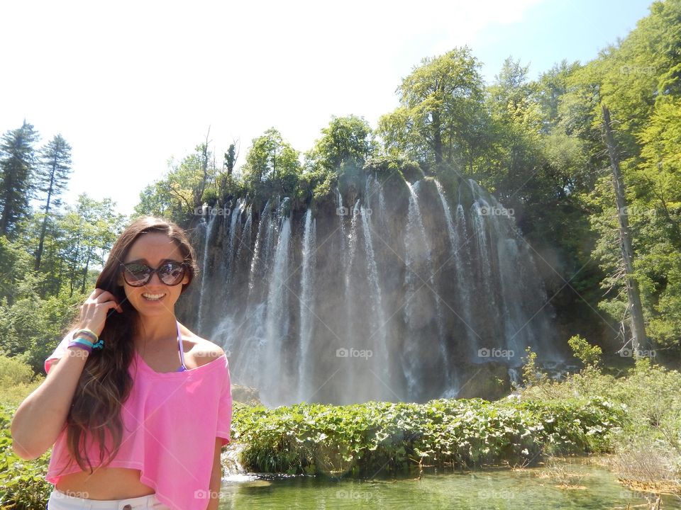 Young woman smiling in front of waterfall