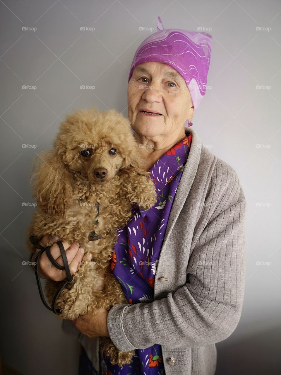 Senior woman holding poodle dog