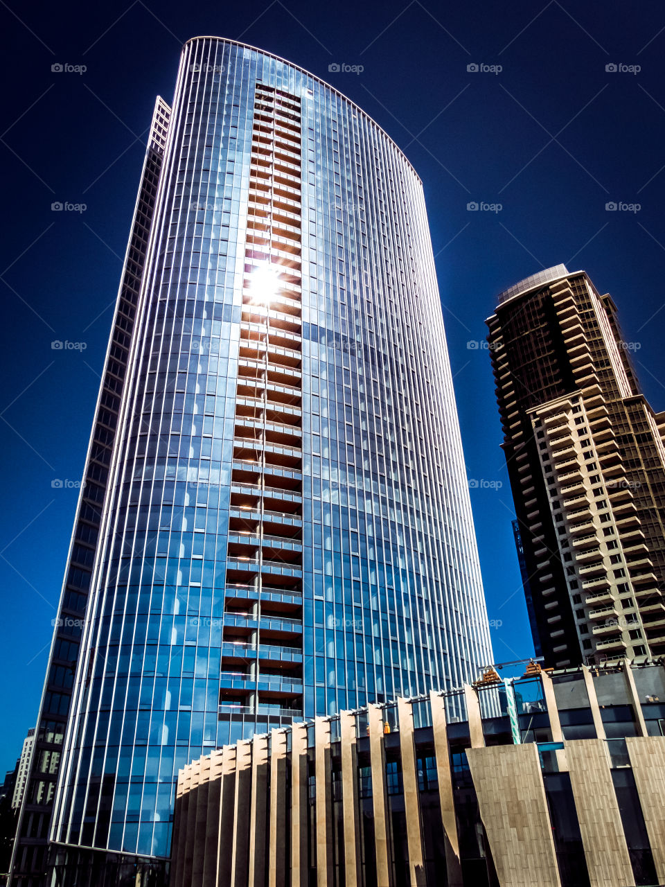 The sun gleaming off of a modern skyscraper of glass in downtown San Diego, California 