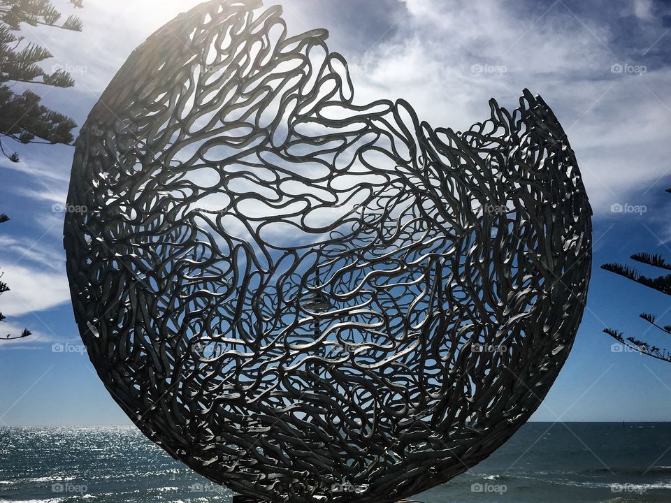 Ocean backdrop for this steel grey artistic globe sculpture in Adelaide, south Australia 