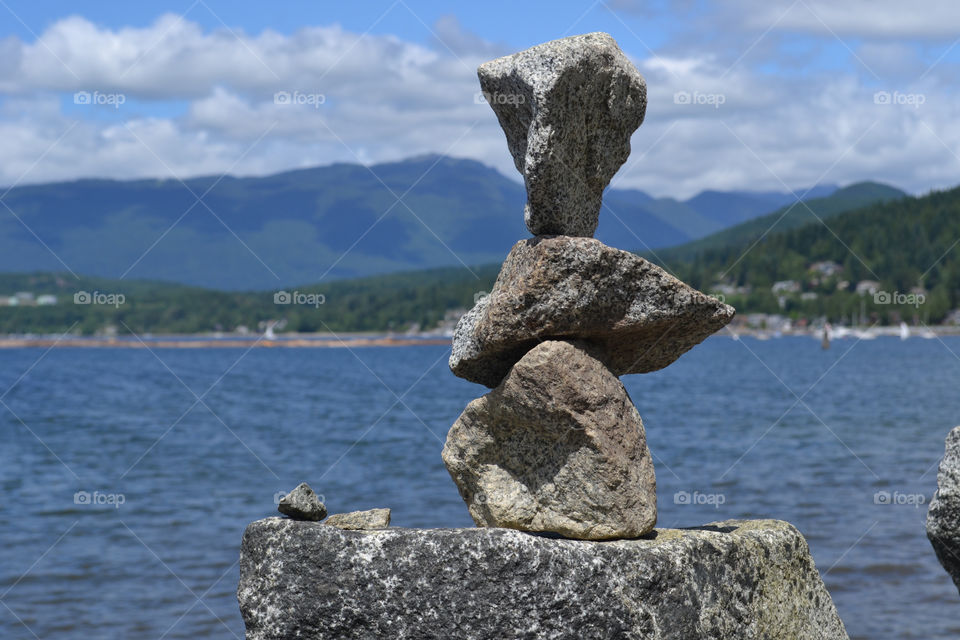 Rock stack on ocean edge overlooking vancouver's north shore and west coast mountains
