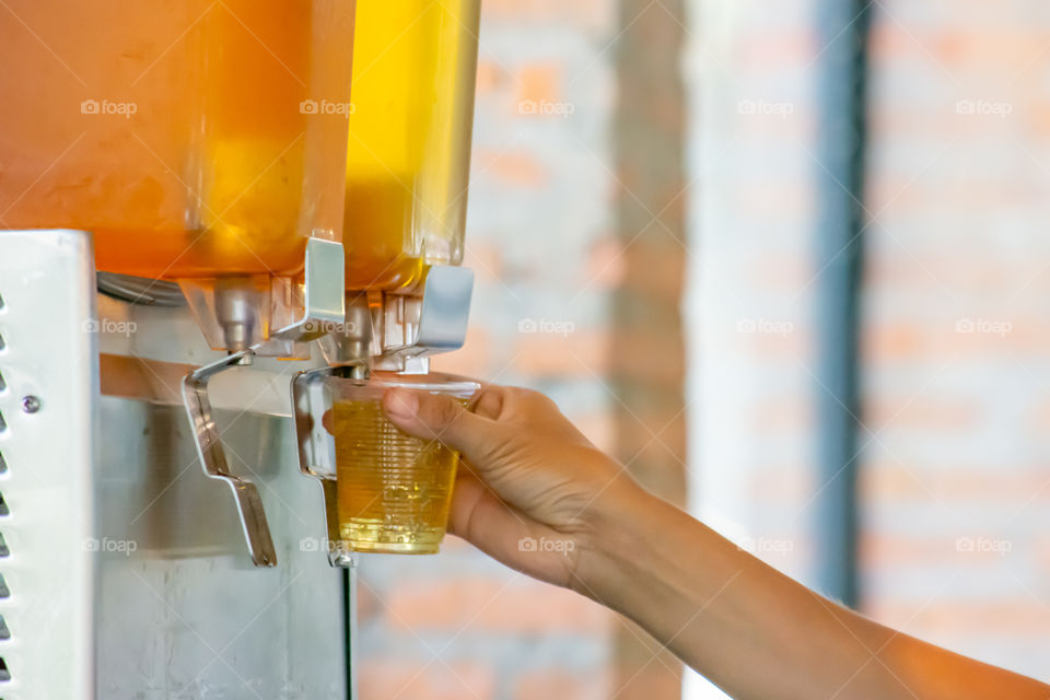 The hand holding the cup plastic flush tea from Juice Dispensor.