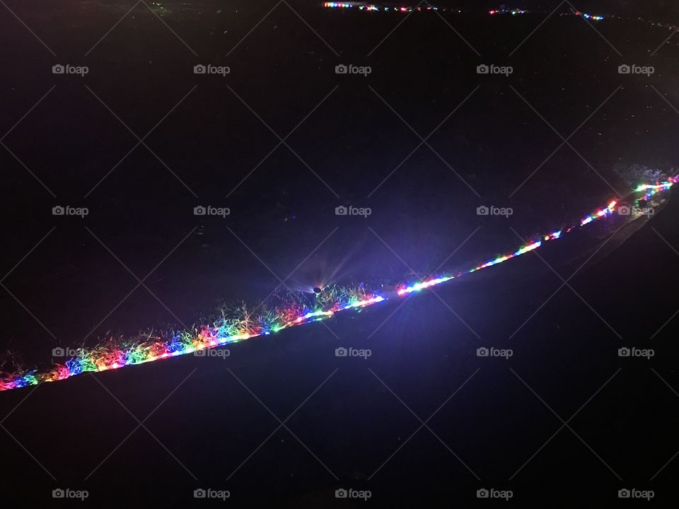 A row of red, green, blue, pink, Christmas lights lining up the lawn on a cool night in December. USA, America