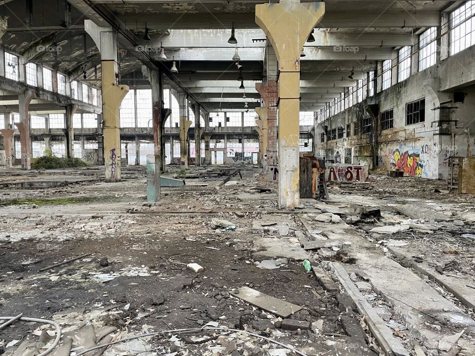 Interior of abandoned industrial hall from an old factory full of mess. Brownfield with broken windows and damaged and sprayed walls.