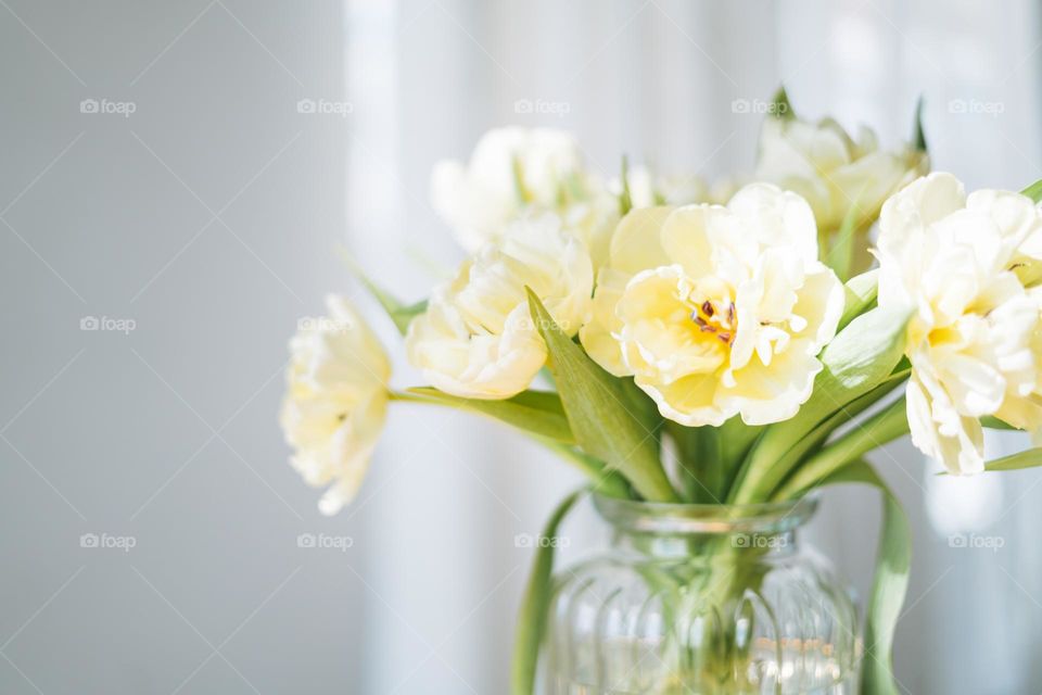 Beautiful bouquet of yellow tulips in vase at the home, natural background