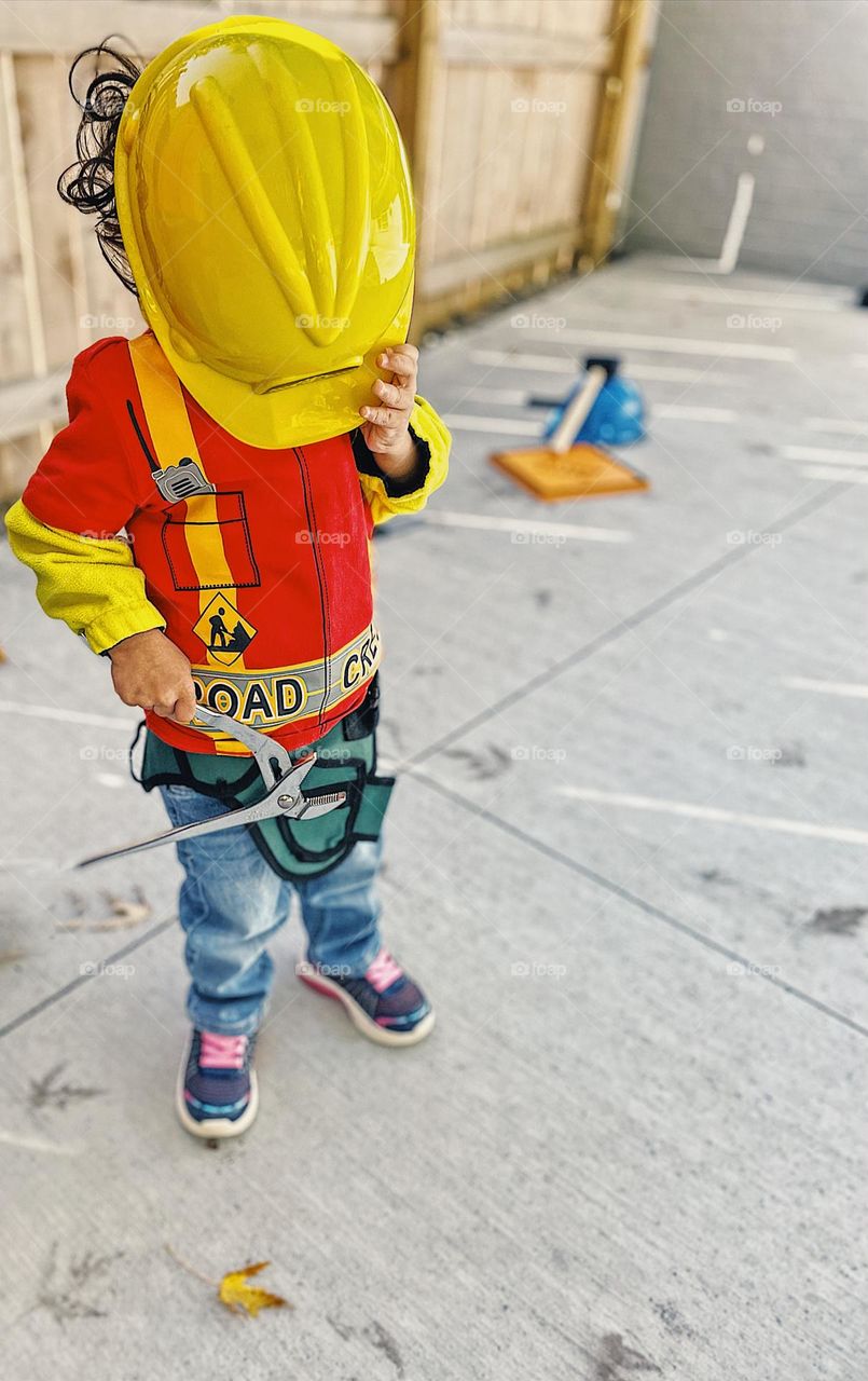 Little girl with yellow construction worker hat on, yellow hard hat, toddler wearing hard hat, construction worker outfit, cute little toddler outfit, road crew toddler, bright yellow