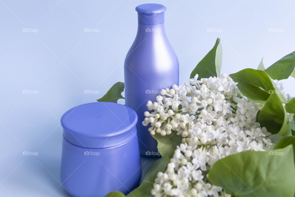 Jars with cosmetic products, beauty cosmetics in purple jars with fragrant flowers.