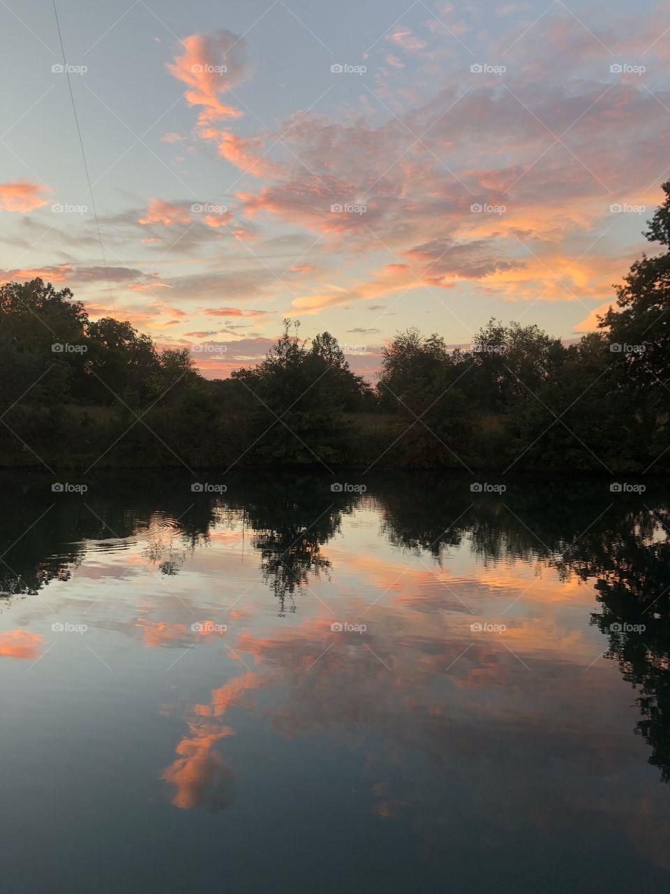 Cloudscape color reflection of sunset in still pond water