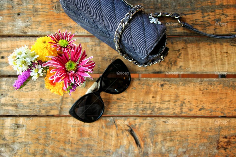 Accessories for girls  In coming out to travel and chill  Was placed on a wooden table  With shoulder bag  Glasses, etc.