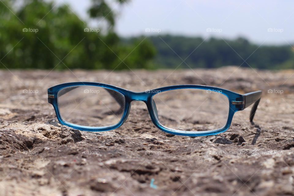 A pair of blue glasses lies on a rock