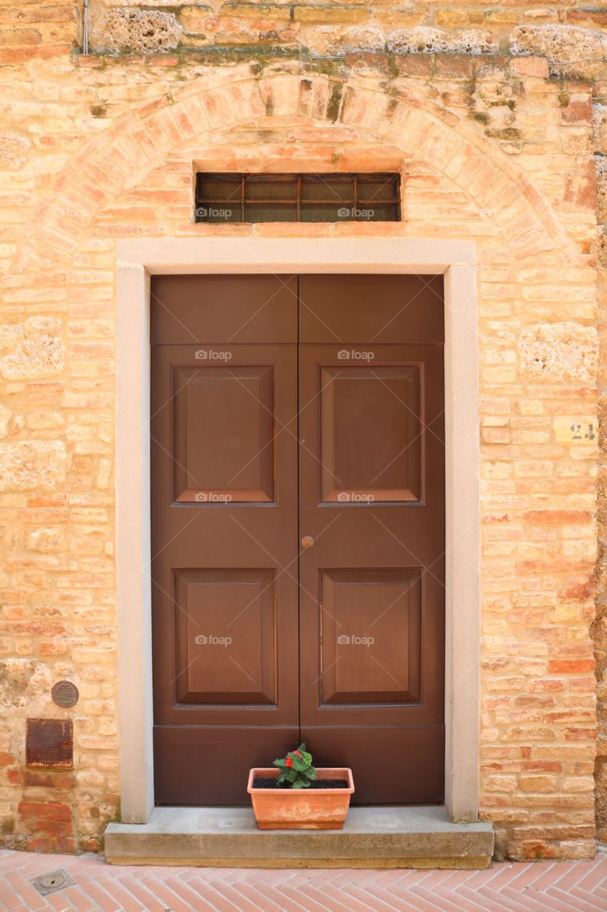 Porta Toscana marrom em muro alaranjado de tijolos, vintage 