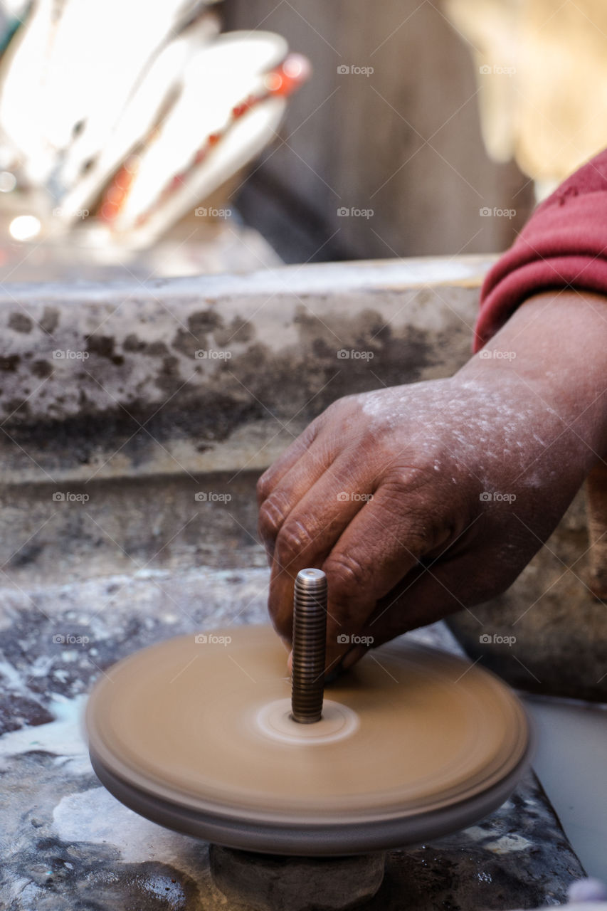 This man's job is to use this machine to turn big stones into lovely little soft and clear pieces of gems, to be used later as accessories or part of decoration. You will see different angles of the same hand and job.