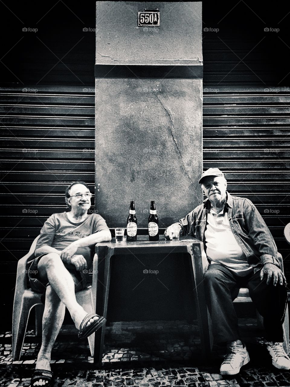 Two guys, two beers . Two old man stares at my camera while drinking some beer in a hot afternoon. 