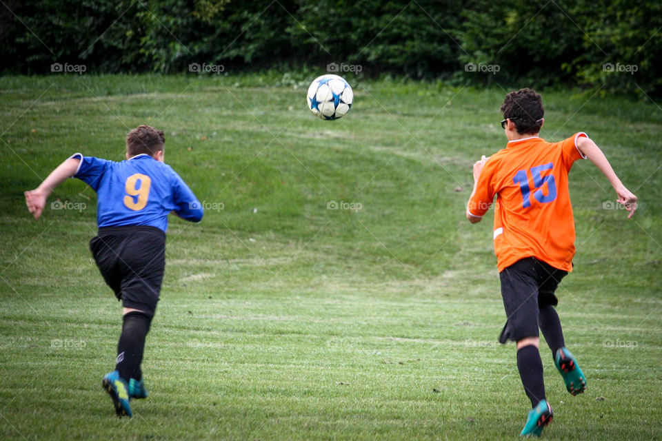 Two soccer players are running after the ball