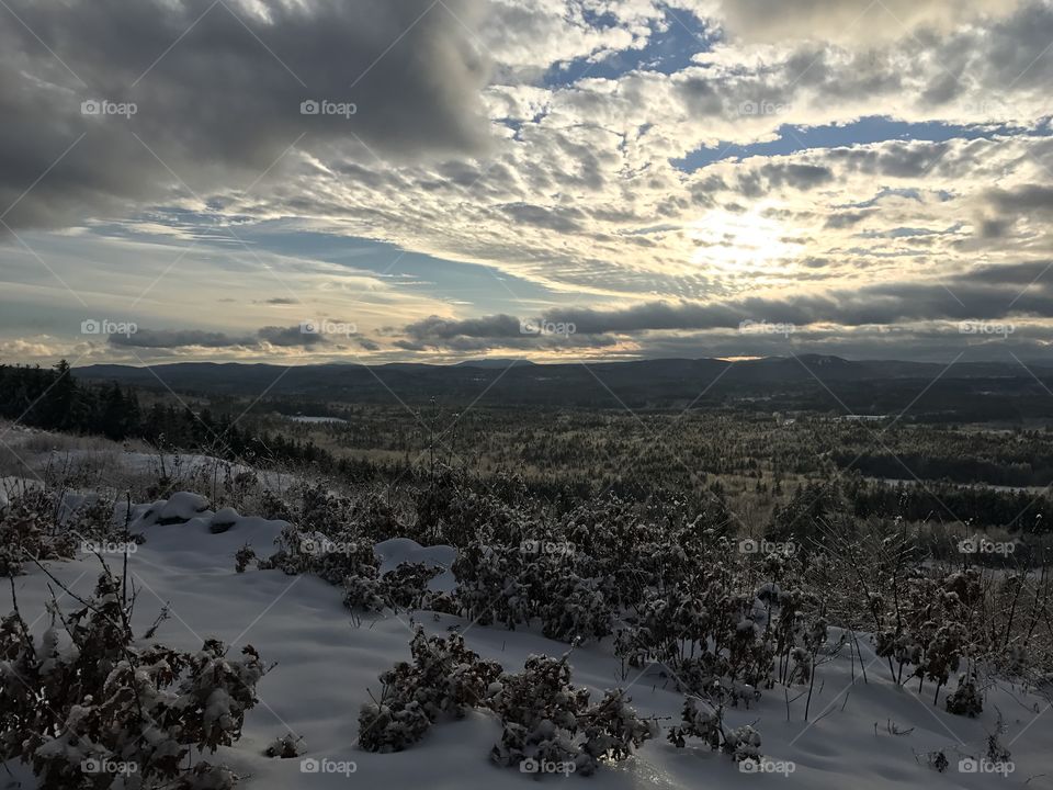 Sun peeking through clouds across mountain range