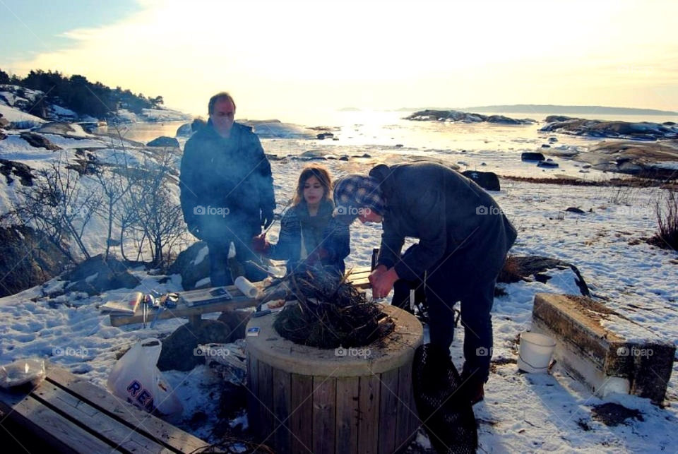 People making a fire. Father and his teens making a fire outdoor a cold winter day