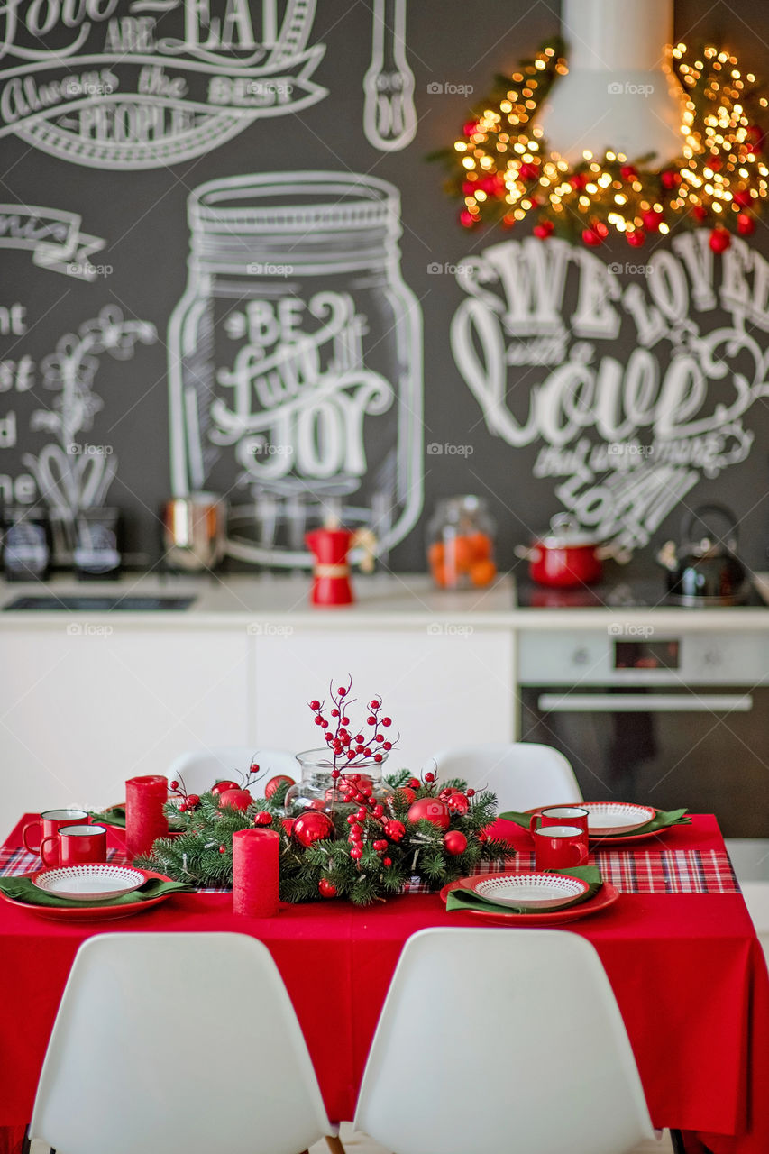 Festive winter cozy kitchen interior with garlands, decorations and gifts.  Christmas dinner at the decorated table.