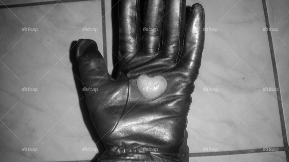 Black gloves holding heart shaped ice.