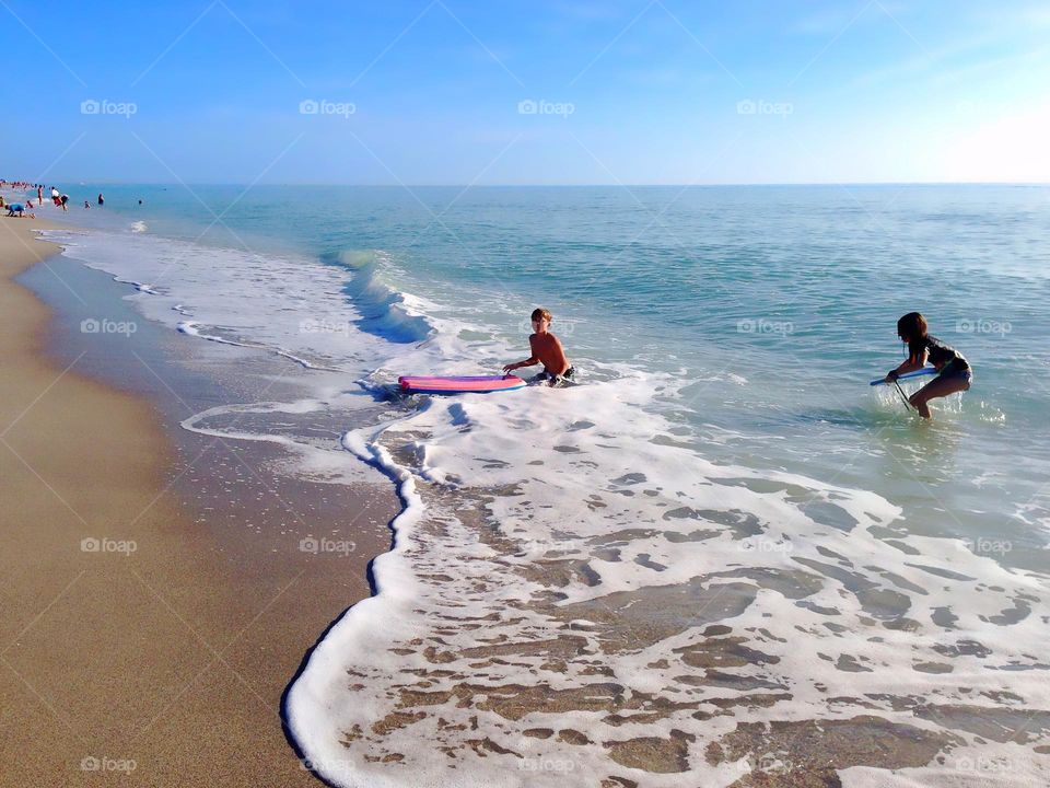 Children playing in the ocean surf on their boogie boards.