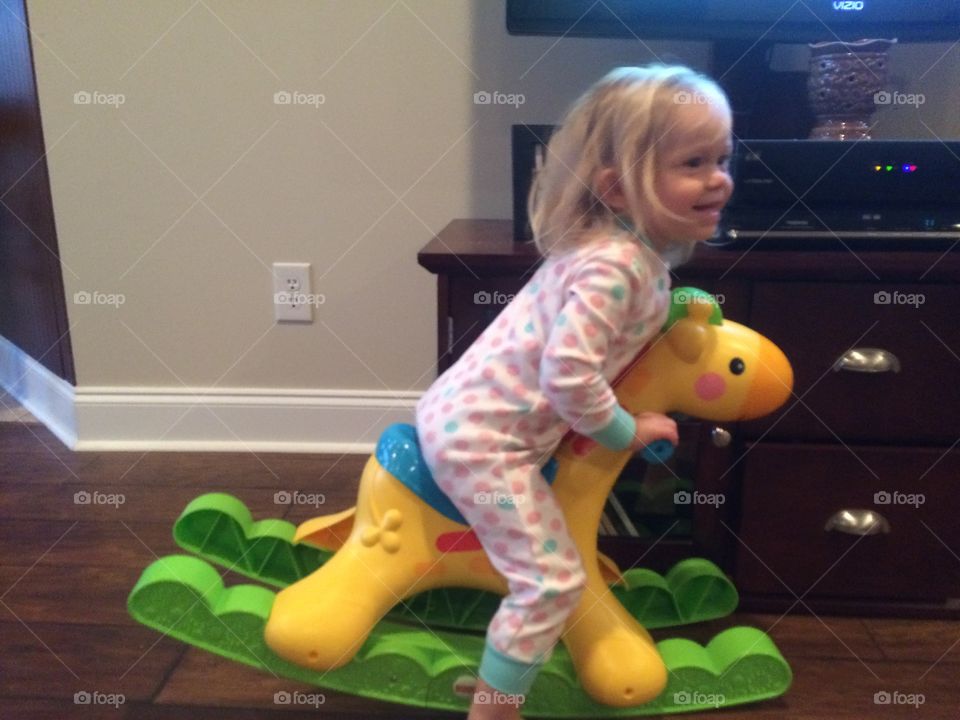 Cute baby girl riding giraffe rocker