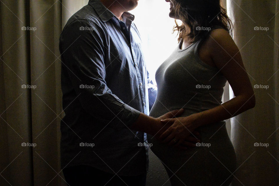 Happy couple standing against window