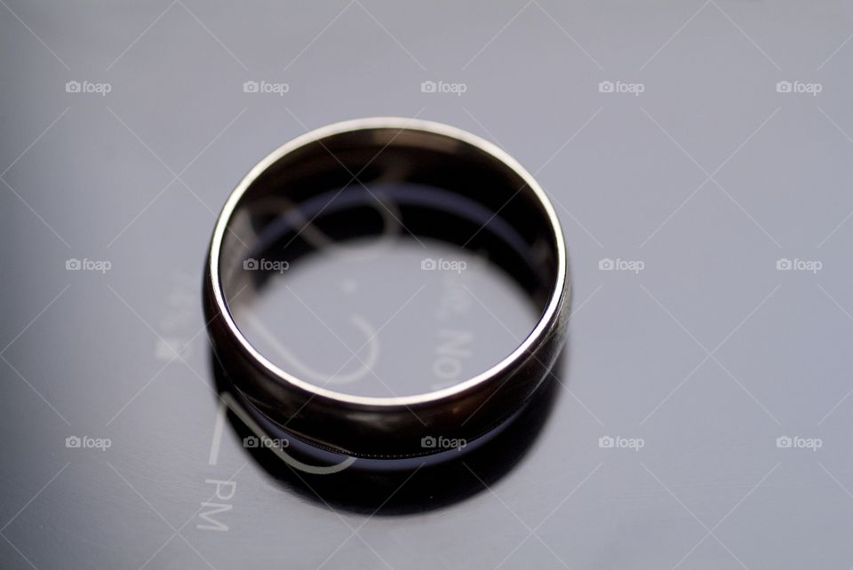 A wedding band sits atop a cell phone.