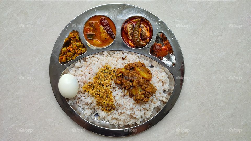 Indian rice meal which includes Sambar and fish curry, spicy curry from India,  Indian vegetarian and non-vegetarian curry, food from India, Thoran(left end) and lemon pickle (right end)