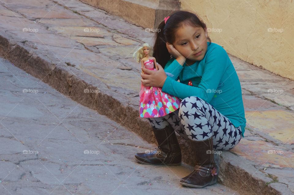 A candid capture of a young girl seated on the  the sidewalk in San Miguel de Allende, Mexico 