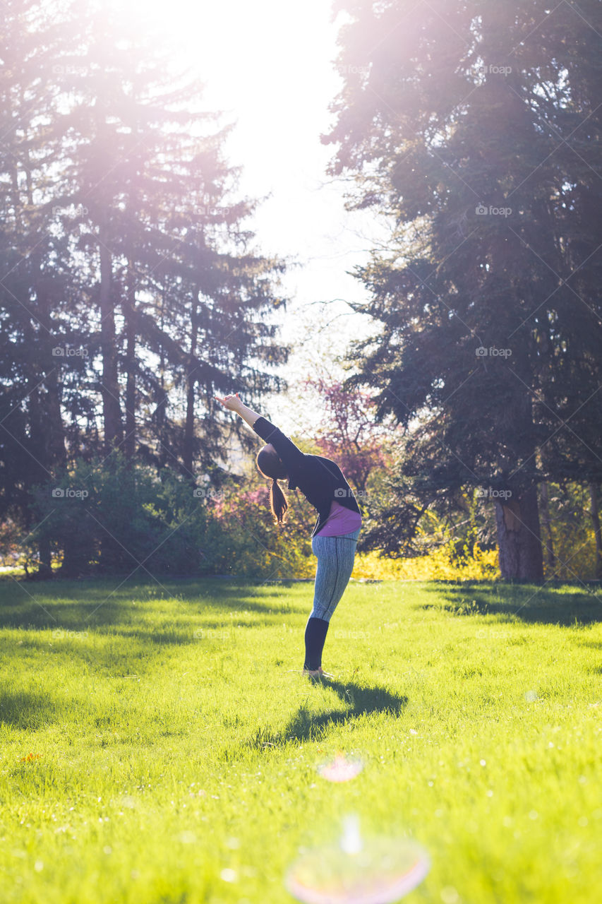 A woman practices yoga outside on a sunny summer afternoon 