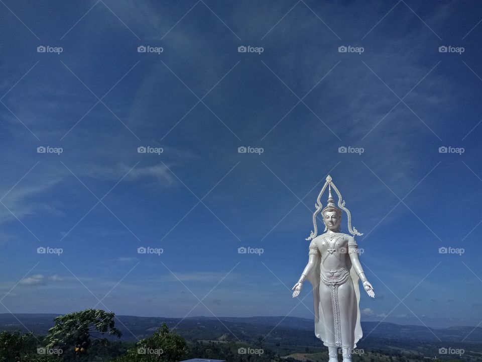 Sculpture of Buddhism with mountain view and blue sky.