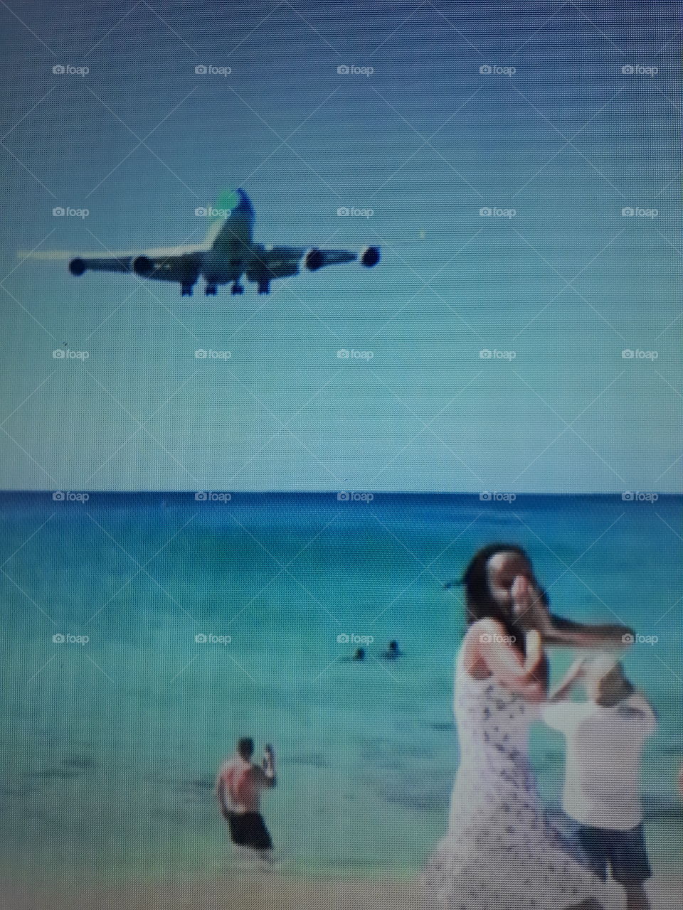 A large plane preparing to land at one of the most dangerous airports in the world near the crowded tourist beach.