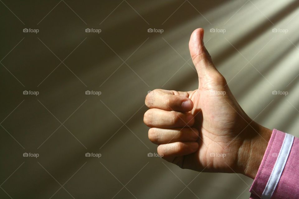 Close-up of a person's hand making a thumbs up sign