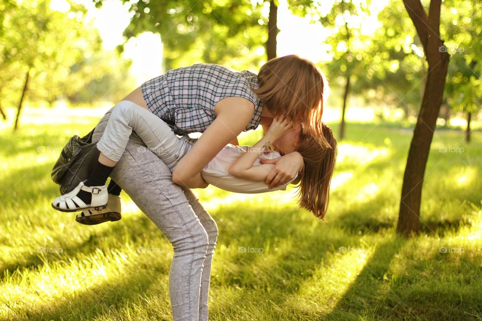 Mom kisses her daughter in the summer in the park