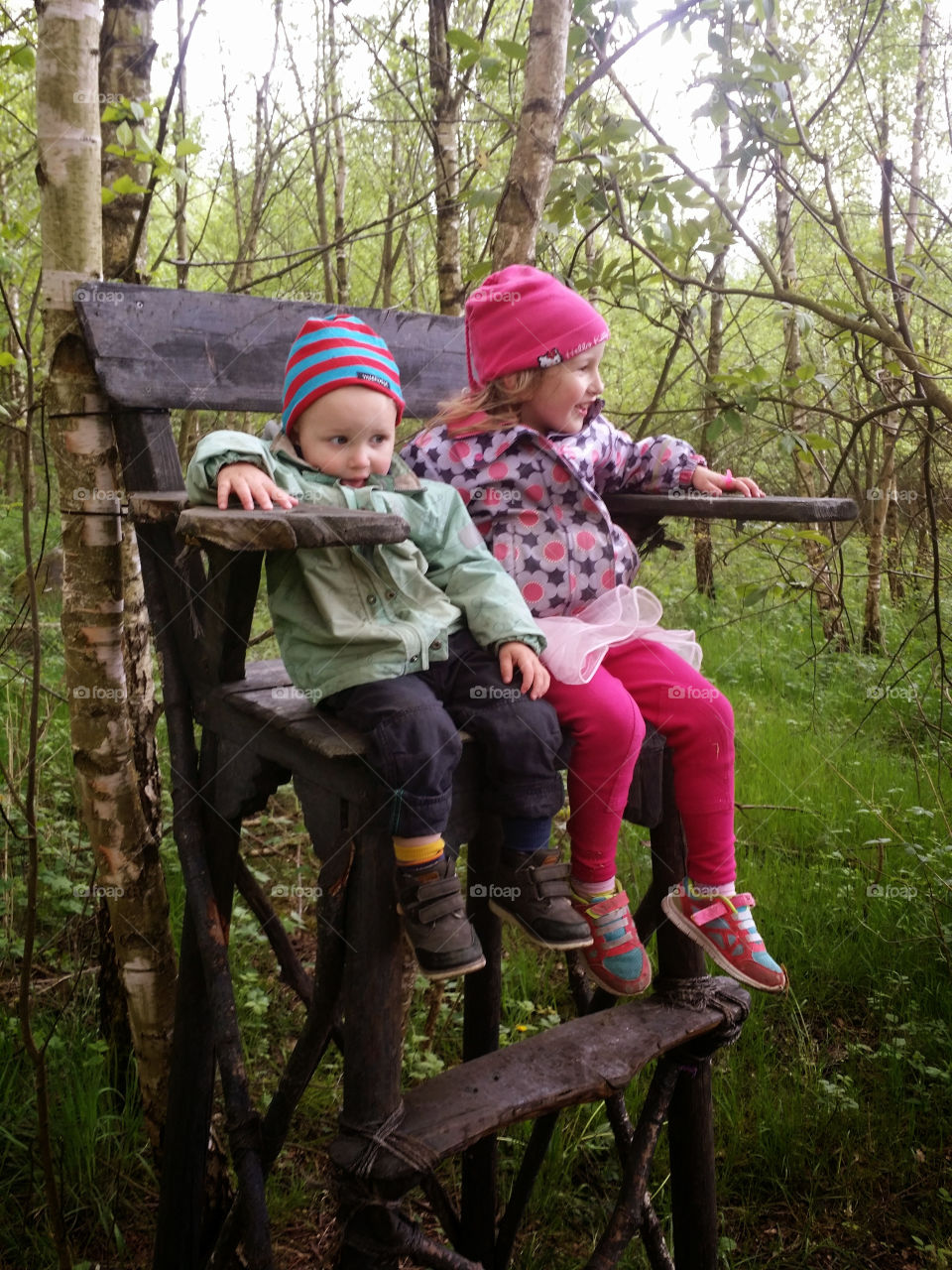 Two kids on a high chair in the forest