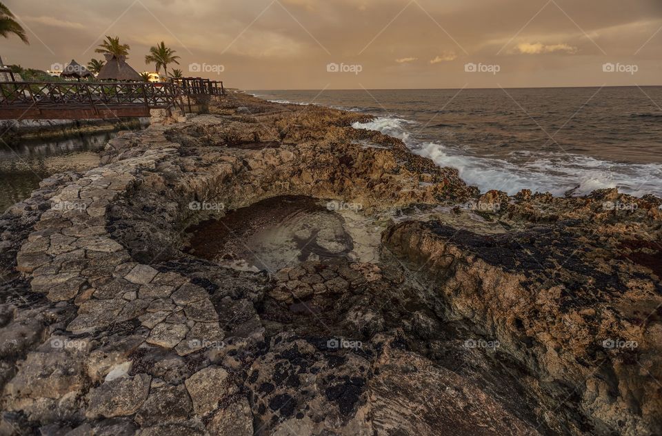 Beautiful natural swimming pool in the rocky coast at sunset in Puerto Aventuras in mexico.