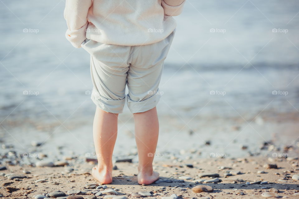 Little girl walking on the sea shore at sunny morning 