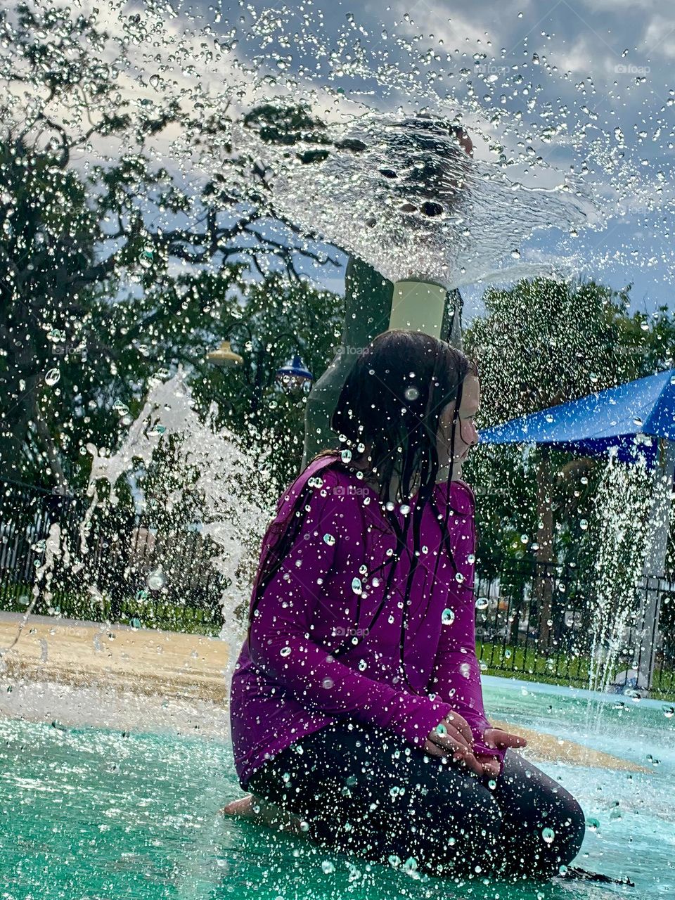 Children having lots of fun in the water at the colorful kids splash pad at the city park for children during a really warm day in Florida.