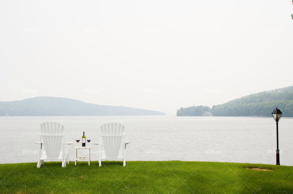 To Adirondack chairs wine and wine glasses on the shores of Lake