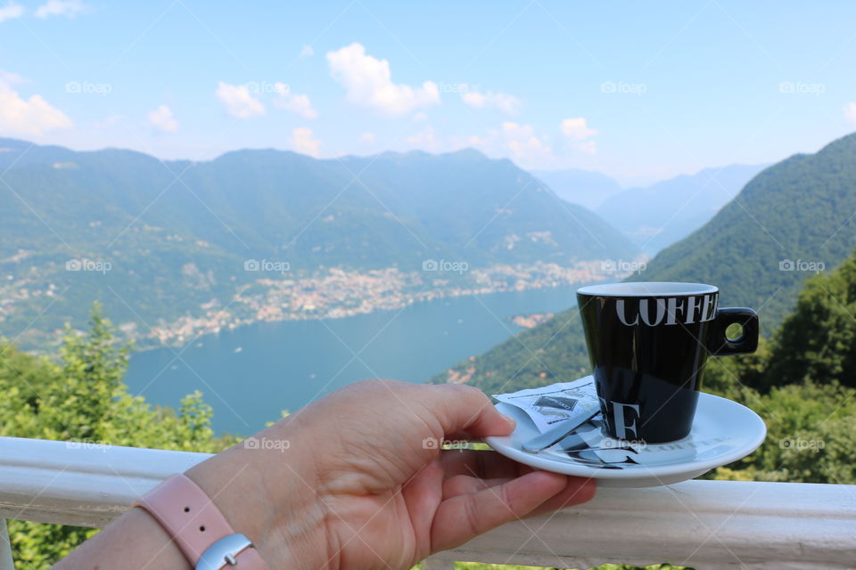 Having coffee on a balcony overlooking the beautiful scenery of lake Como , little towns  around it and mountains above it