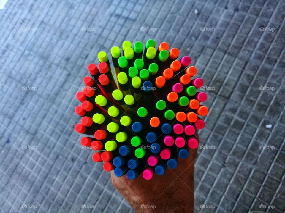 A hand holds so many colored pens