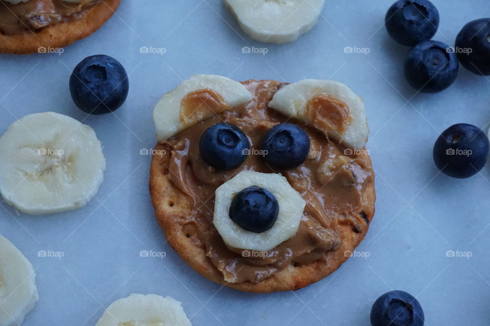 Funny face healthy snack using a cracker with peanut and pecan nut spread ... banana and blueberries 