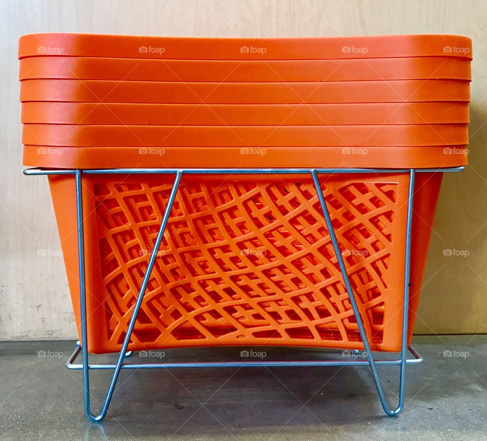Stacked handheld orange shopping baskets