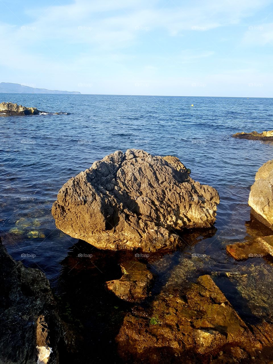 Big stone over the clear and blue sea at L'Escala, Catalonia