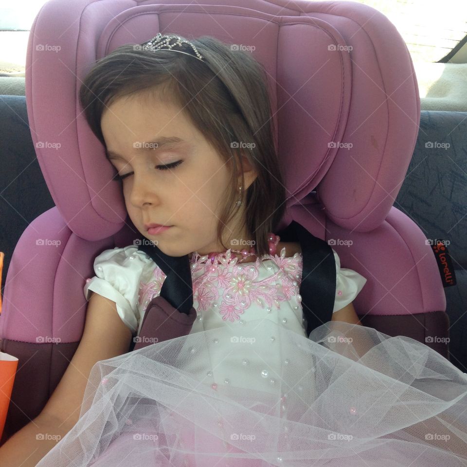 Little girl dressed up as a princess sleeping in the car