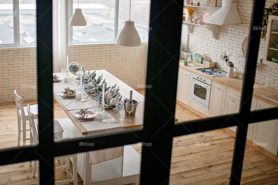 Festive winter cozy kitchen interior with garlands, decorations and gifts.  Christmas dinner at the decorated table.