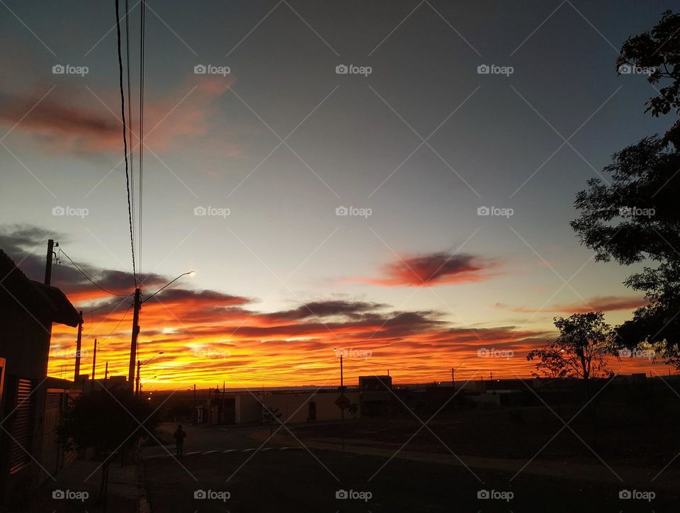 A sky with multicolored clouds announcing the dawn on a deserted street in a small town in the interior...