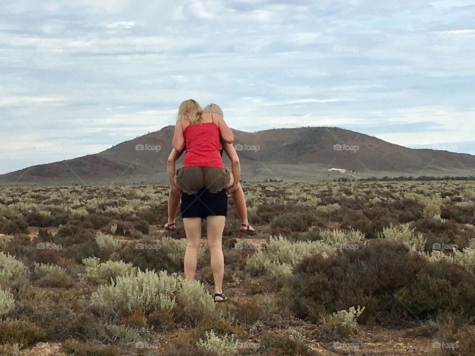 Young woman in red singlet top on a piggy back ride in Australian outback