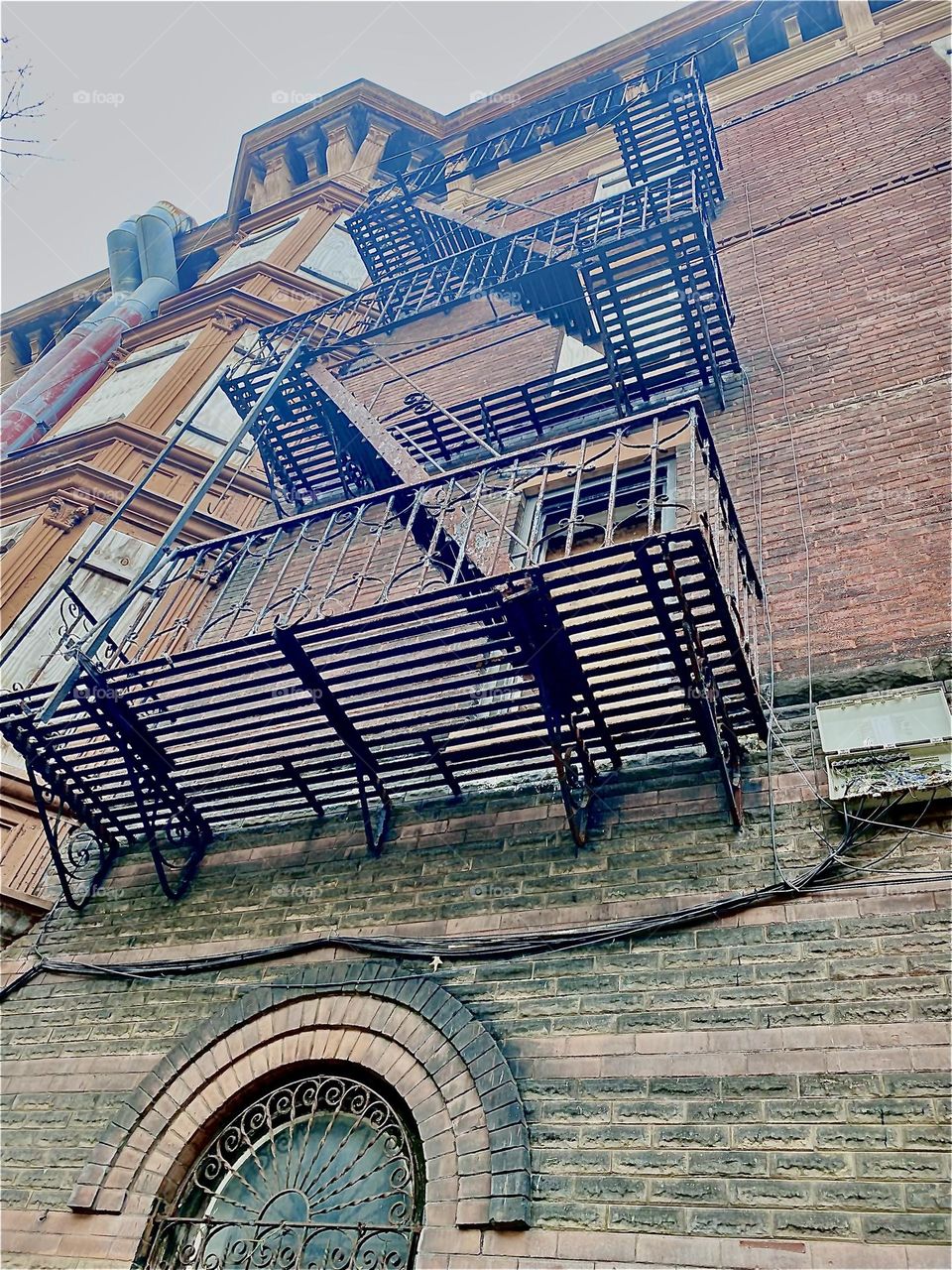 This building on “Waverly St” in “Clinton Hill”, Bklyn has interesting detail like the iron cast fire escape with steps and ladders, an exposed brick facade and old fashioned architecture such as rounded windows and stucco. 2023. Hypnotic Productions